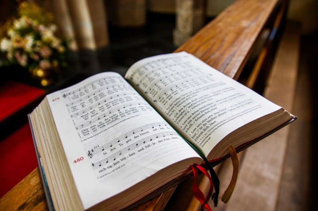 An open hymnal resting on a wooden pew in a church