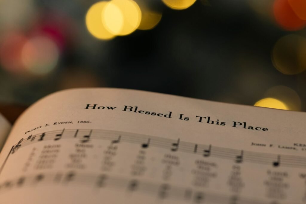 Open hymn sheet music, the page headed How Blessed Is This Place, with warm light behind